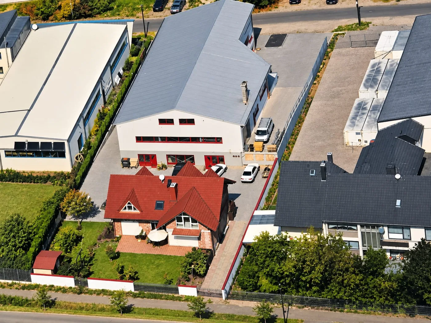 Luftbild des Betriebs am Hessenring 13: Werkstatt mit Büro, Hof mit Firmenwagen und das Wohnhaus davor