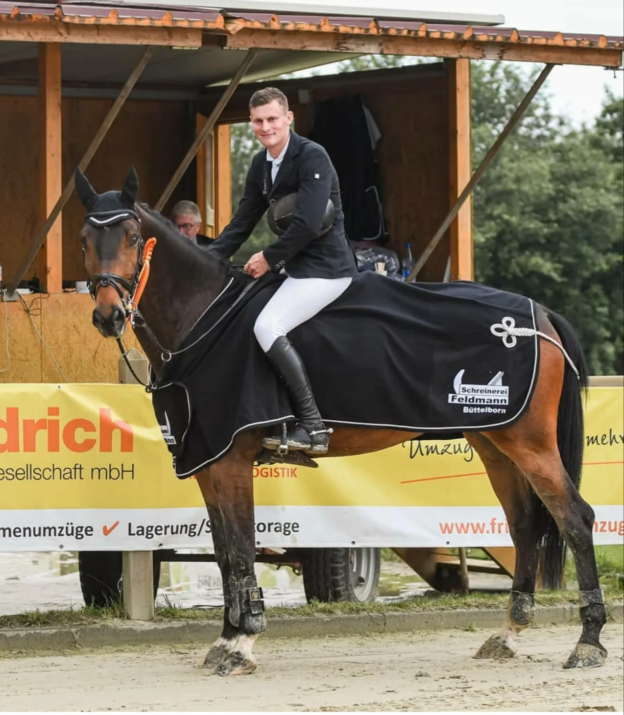 Reiter auf einem Turnier, das Pferd trägt eine Decke mit dem Zeichen der Schreinerei Feldmann Büttelborn