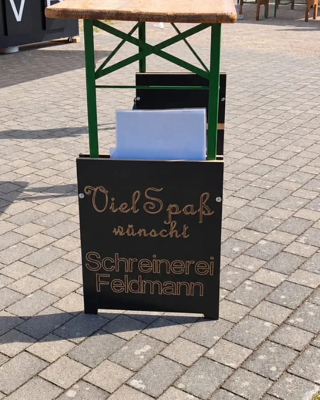 Biertischgarnitur auf einem Vereinsfest mit der Tafel „Viel Spaß wünscht Schreinerei Feldmann“